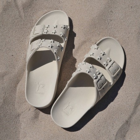 sandales blanches avec clous en forme d'étoile cacatoès sur le sable